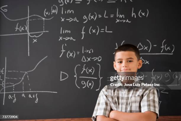 Hispanic Boy Smiling In Front Of Math Formula On Blackboard, Foto de stock