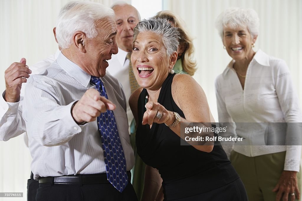 Senior couple at party pointing in surprise