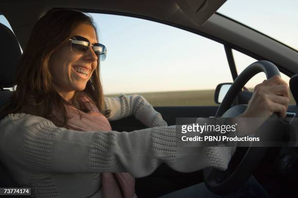young woman driving car - fahrspaß stock-fotos und bilder