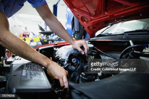 close up of male auto mechanic working on engine in auto repair shop - vehicle hood stock pictures, royalty-free photos & images