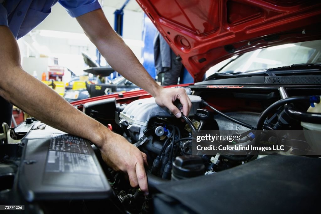 Close up of male auto mechanic working on engine in auto repair shop
