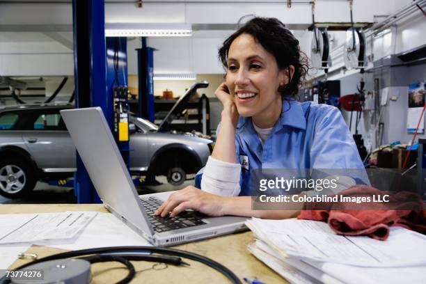 female auto mechanic using laptop in auto repair shop - mechanic computer stock pictures, royalty-free photos & images