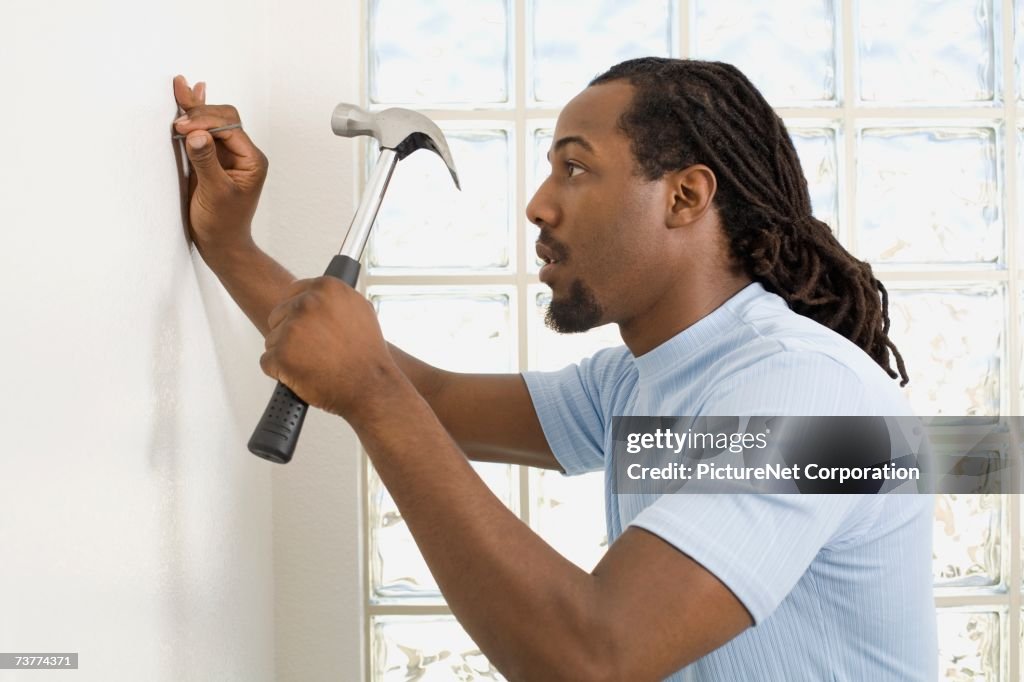 African Man Hammering Nail Into Wall High-Res Stock Photo - Getty Images