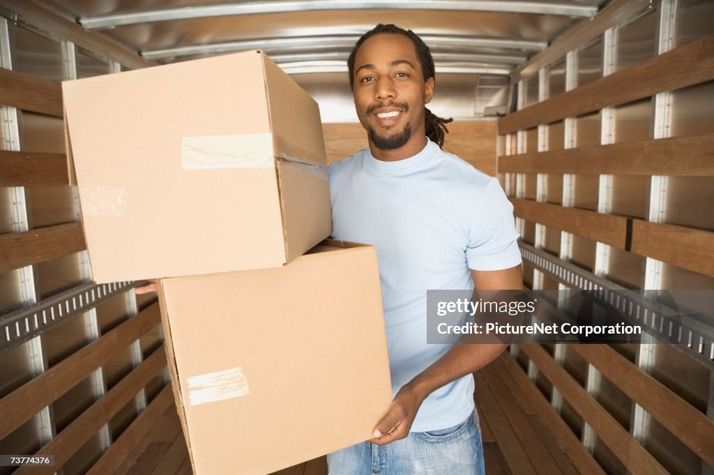 African man in moving truck holding boxes