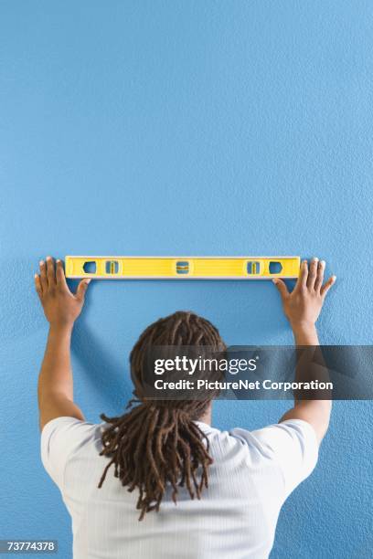 rear view of african man using level on wall - dreadlocks back stock pictures, royalty-free photos & images