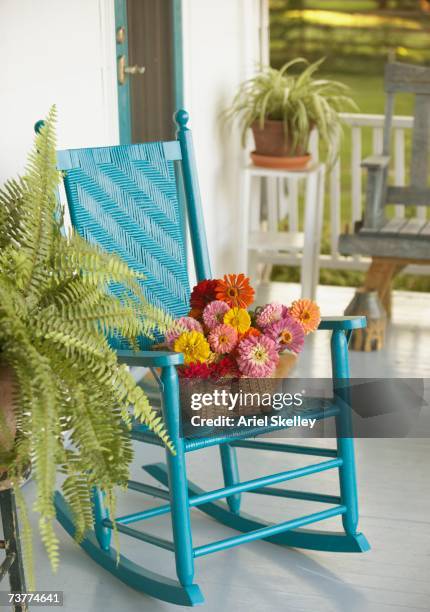 basket of flowers and rocking chair on porch - schaukelstuhl stock-fotos und bilder