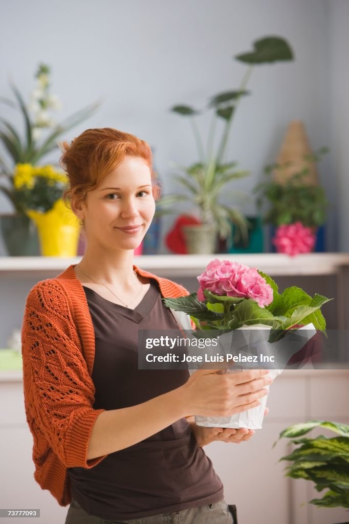 Hispanic woman holding potted plant in florist shop