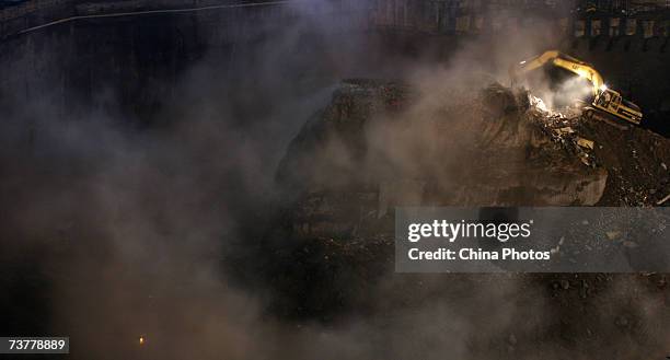 An excavator demolishes a building sitting on its own island of land amid construction all around it on April 2, 2007 in Chongqing Municipality,...