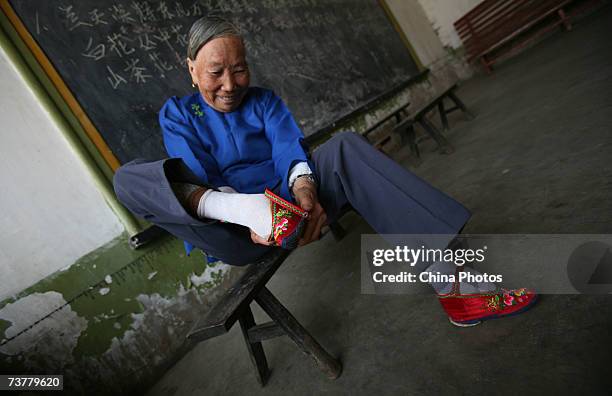 Member of the Bound Feet Women Dancing Team, puts on her "Three Cuns Golden Lotus" shoe as she prepares for dancing practice at Liuyi Village on...
