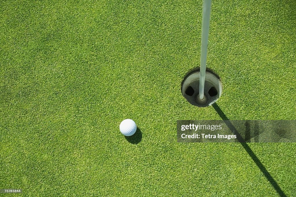 Golf ball near cup on putting green outdoors