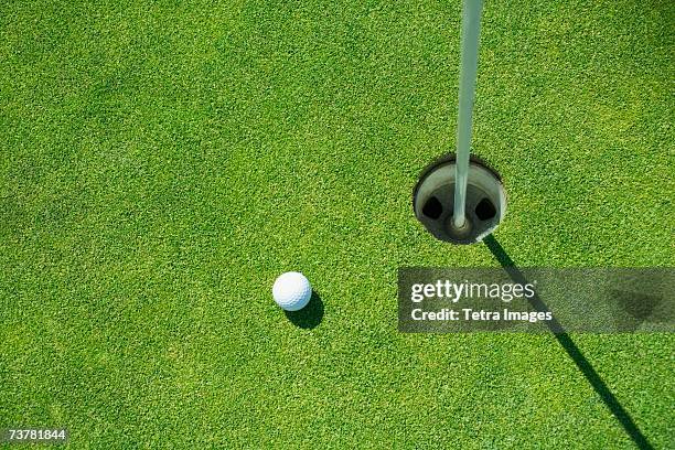 golf ball near cup on putting green outdoors - green de golf imagens e fotografias de stock