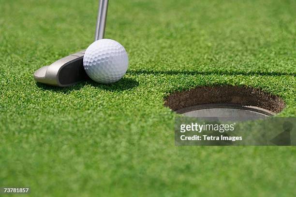 close-up of golf ball and club near cup - golf putter stock pictures, royalty-free photos & images
