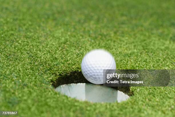 golf ball dropping into hole on green - golf green hole stock pictures, royalty-free photos & images