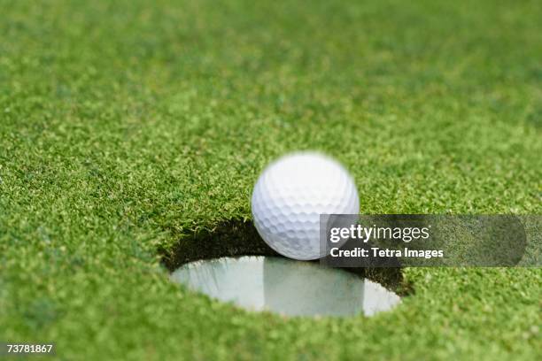 golf ball dropping into hole on green - accurate stock pictures, royalty-free photos & images