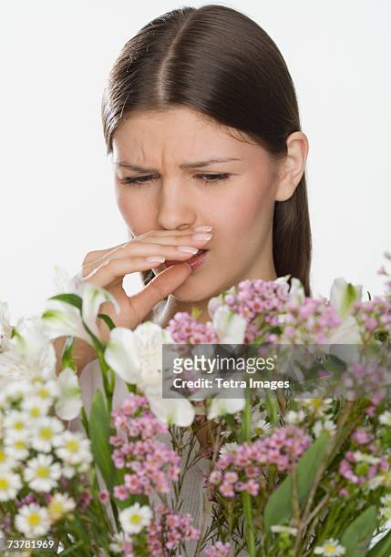woman about to sneeze and holding flowers - closeup of a hispanic woman sneezing foto e immagini stock