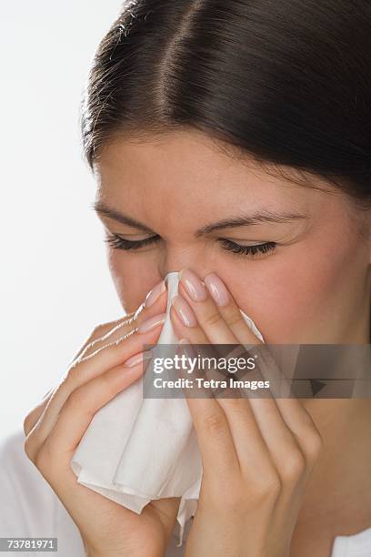 close up of woman blowing nose - closeup of a hispanic woman sneezing foto e immagini stock