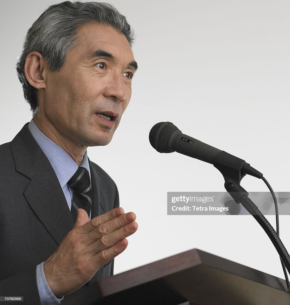 Senior Asian businessman speaking at podium