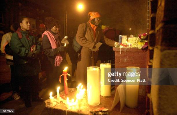 People attend a candlelight vigil for Amadou Diallo February 4, 2001 in the Bronx borough of New York City beside the doorway where the West African...