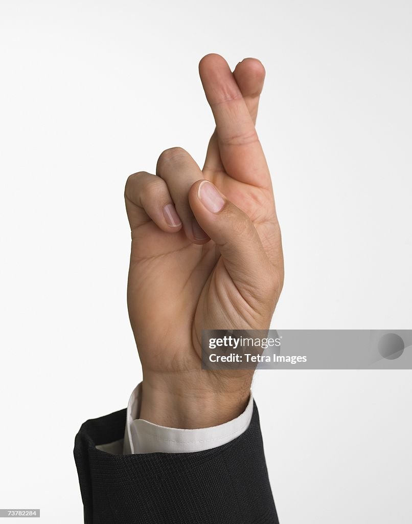 Studio shot of businessman's hand with fingers crossed