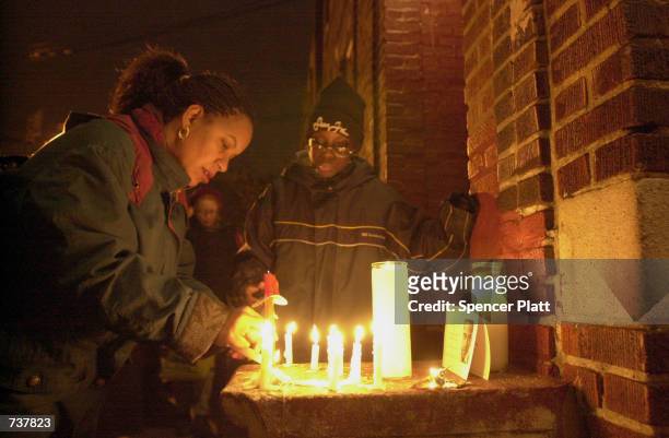 Woman lights a candle at a vigil for Amadou Diallo February 4, 2001 in the Bronx borough of New York City beside the doorway where the West African...