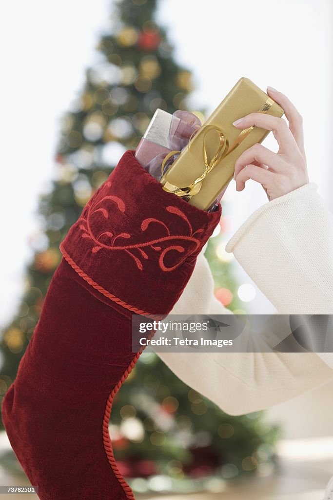 Woman stuffing gifts into Christmas stocking