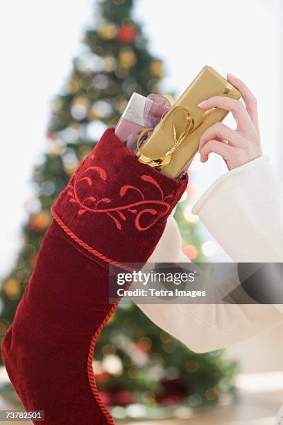 woman stuffing gifts into christmas stocking - stockings stock pictures, royalty-free photos & images