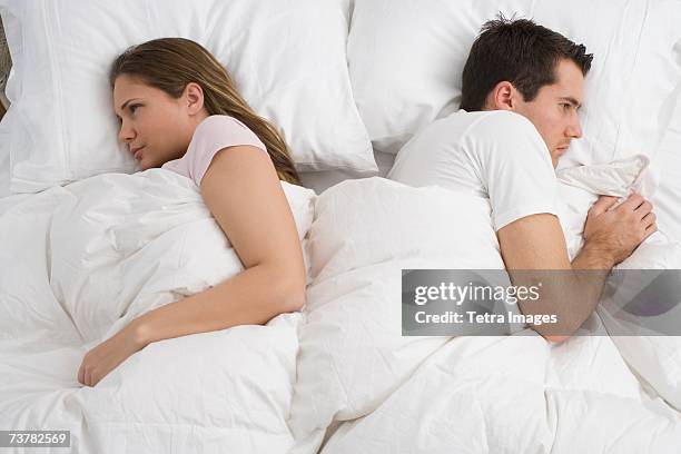 angry couple laying in bed - complaining foto e immagini stock