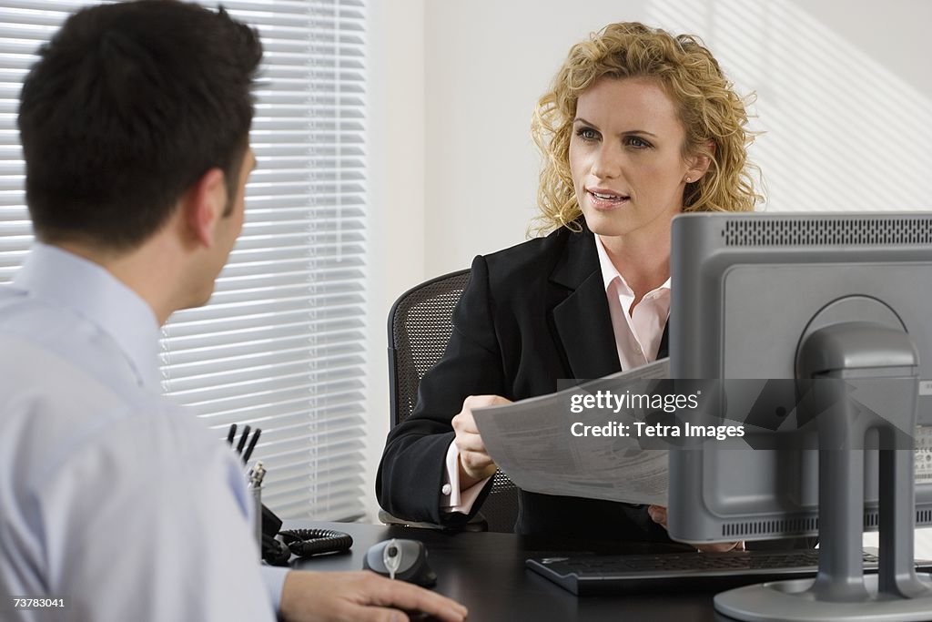 Businesswoman consulting with businessman at desk