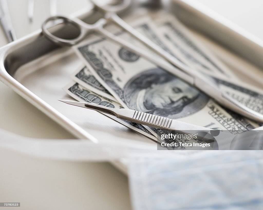 Close up of surgical tools and money