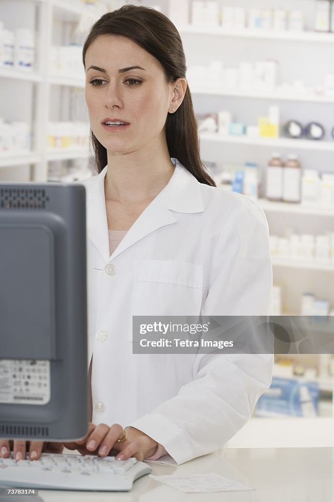 Female pharmacist typing on computer