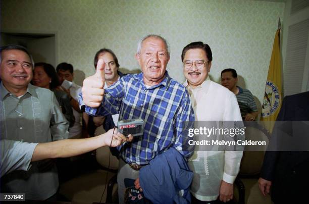 French fugitive businessman Alfred Sirven, center, gives the thumbs-up sign as Philippine Justice Secretary Hernando Perez, right, looks on February...