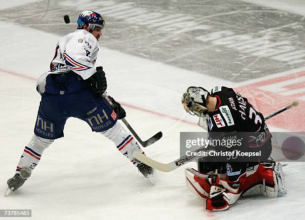 Christoph Ullmann of the Adler shoots the puck and goalie Adam Hauser of the Haie saves during the DEL Play Off semi final match between Cologne Haie...