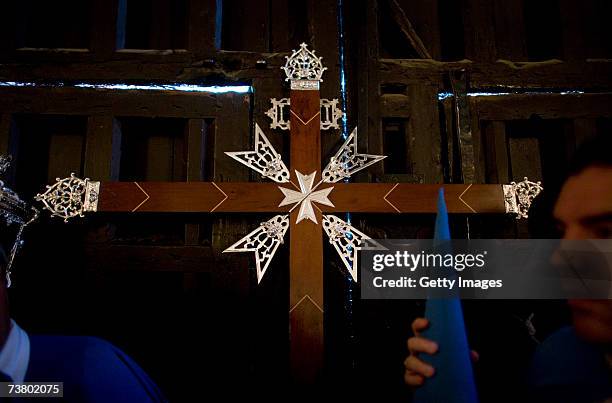 Cross is seen next to members of "San Esteban" brotherhood preparing themselves in the church of San Esteban prior the departure of their procession...