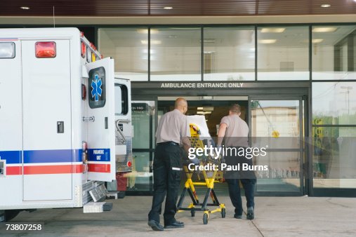 Paramedics taking patient on stretcher from ambulance to hospital Paramedics taking patient on stretcher from ambulance to hospital