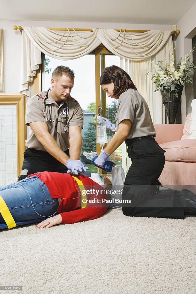 Two paramedics administering CPR to senior patient on floor