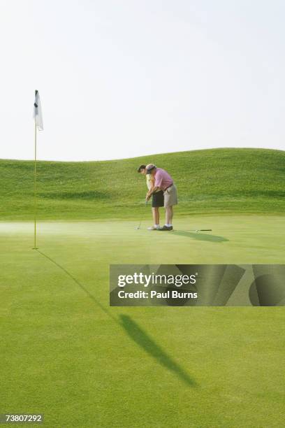 man helping woman to hit golf ball - tuition assistance stock pictures, royalty-free photos & images