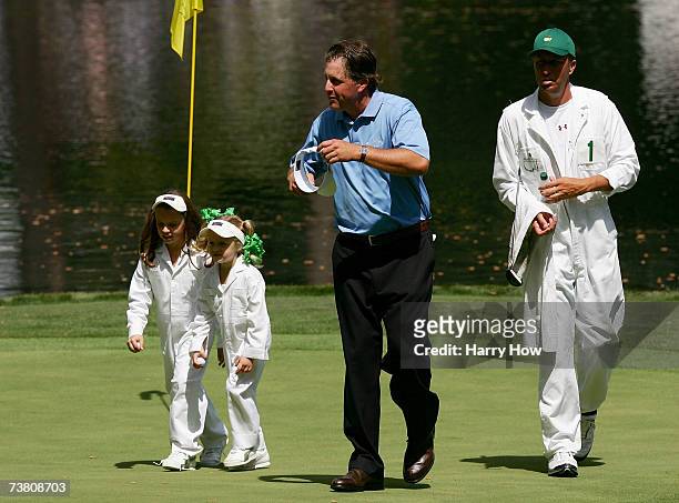 Phil Mickelson walks off the ninth green with his daughters Amanda and Sophia and his caddie Jim Mackay during the Par-3 contest prior to the start...