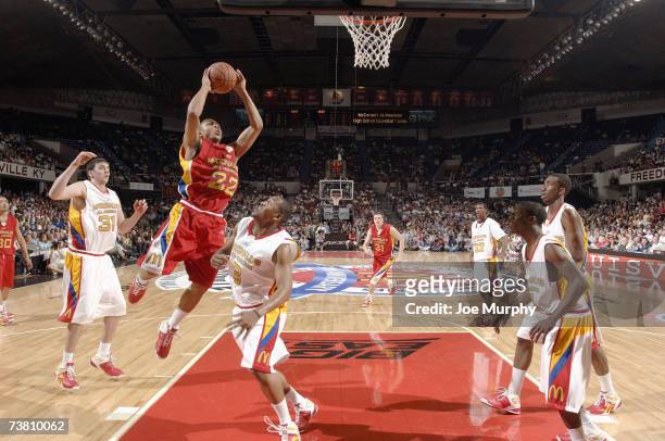 Eric Gordon of the West Team goes to the basket against Kosta Koufos and Austin Freeman of the East Team during the Boy's McDonald's All American...