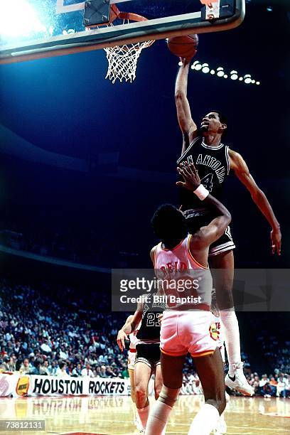 George Gervin of the San Antonio Spurs dunks over Robert Reid of the Houston Rockets during a game played in 1984 at The Summitt in Houston, Texas....