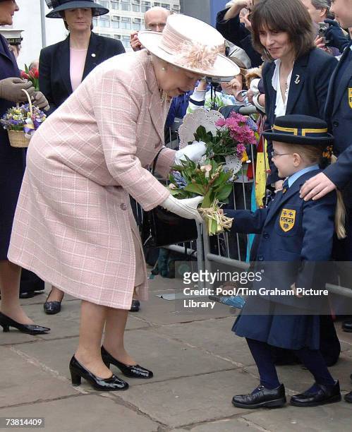 Queen Elizabeth II is presented with flowers by a young schoolgirl during a walkabout outside Manchester Cathedral after attending the traditional...