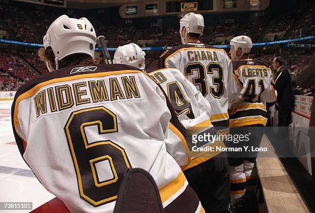 Dennis Wideman, Zdeno Chara and Andrew Alberts of the Boston Bruins look on from the bench against the New Jersey Devils at Continental Airlines...
