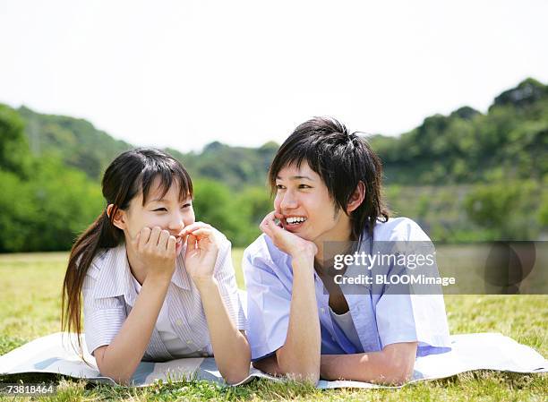 japanese couple lying down on meadow and smiling - only japanese stock pictures, royalty-free photos & images