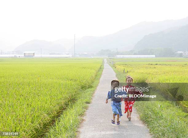 japanese boy and girl wearing yukata running on country road - 女の子走る ストックフォトと画像