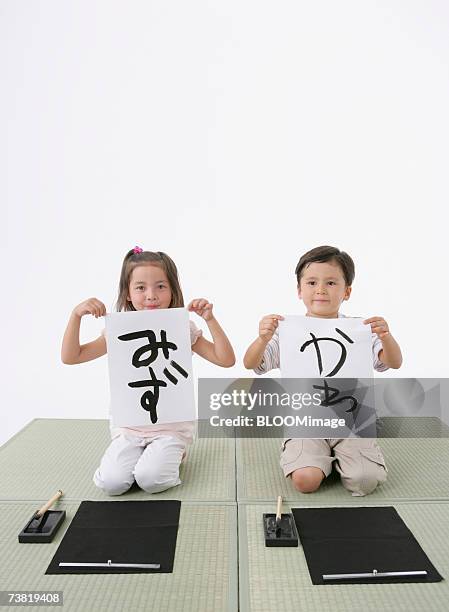 american asian girl and japanese boy sitting on tatami, and writing - japanese calligraphy stock pictures, royalty-free photos & images