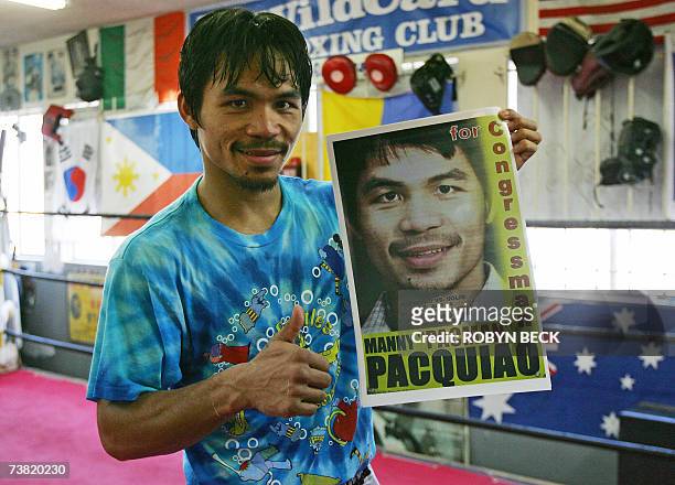 Los Angeles, UNITED STATES: Philippine boxer Manny "Pacman" Pacquiao holds a poster advertising his upcoming title bout during a break in training at...