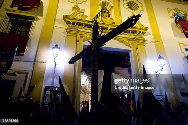 Members of the "Esperanza de Triana" brotherhood carry a Cross outside the Chapel of Los Marineros during their procession during the "Madrugada" on...