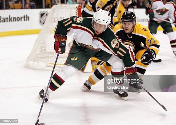 Dominic Moore of the Minnesota Wild skates for the puck against Andrew Ference the Boston Bruins on March 8, 2007 at the TD Banknorth Garden in...