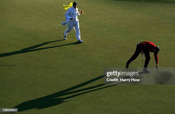 Justin Rose of England collects his golf ball on the 18th hole as his caddie Mick Doran looks on during the third round of The Masters at the Augusta...