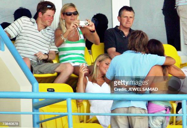 St John's, ANTIGUA AND BARBUDA: Britain's Prince Harry looks on as his girlfriend Chelsy Davy takes pictures of an unidentified couple during the ICC...