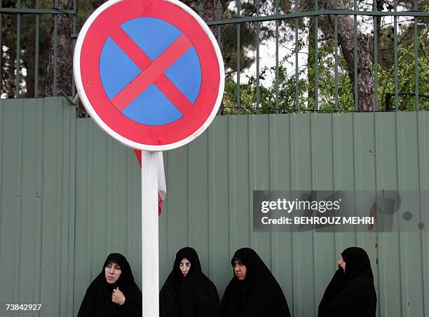 Iranian students stand behind a 'no stopping' road sign during a gathering in support of Iran's nuclear program outside Iran's Atomic Energy...